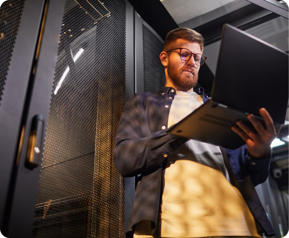 Engineer reviewing a laptop inside a server room