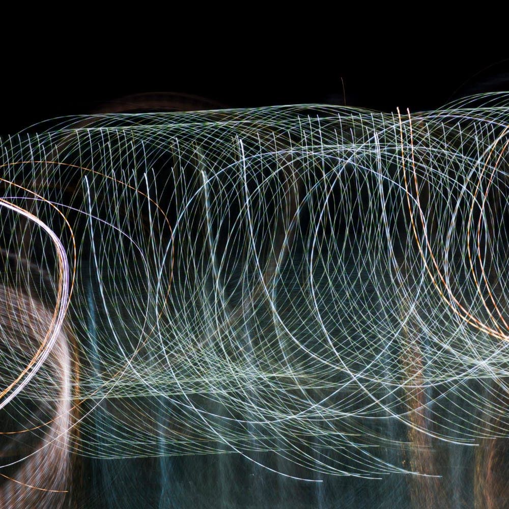 Long-exposure light trails looping through darkness