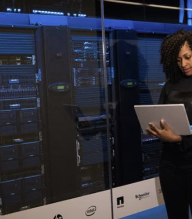 Engineer with a laptop beside illuminated server racks